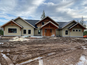 Single-storey gabled home exterior with light siding and wood trim during construction