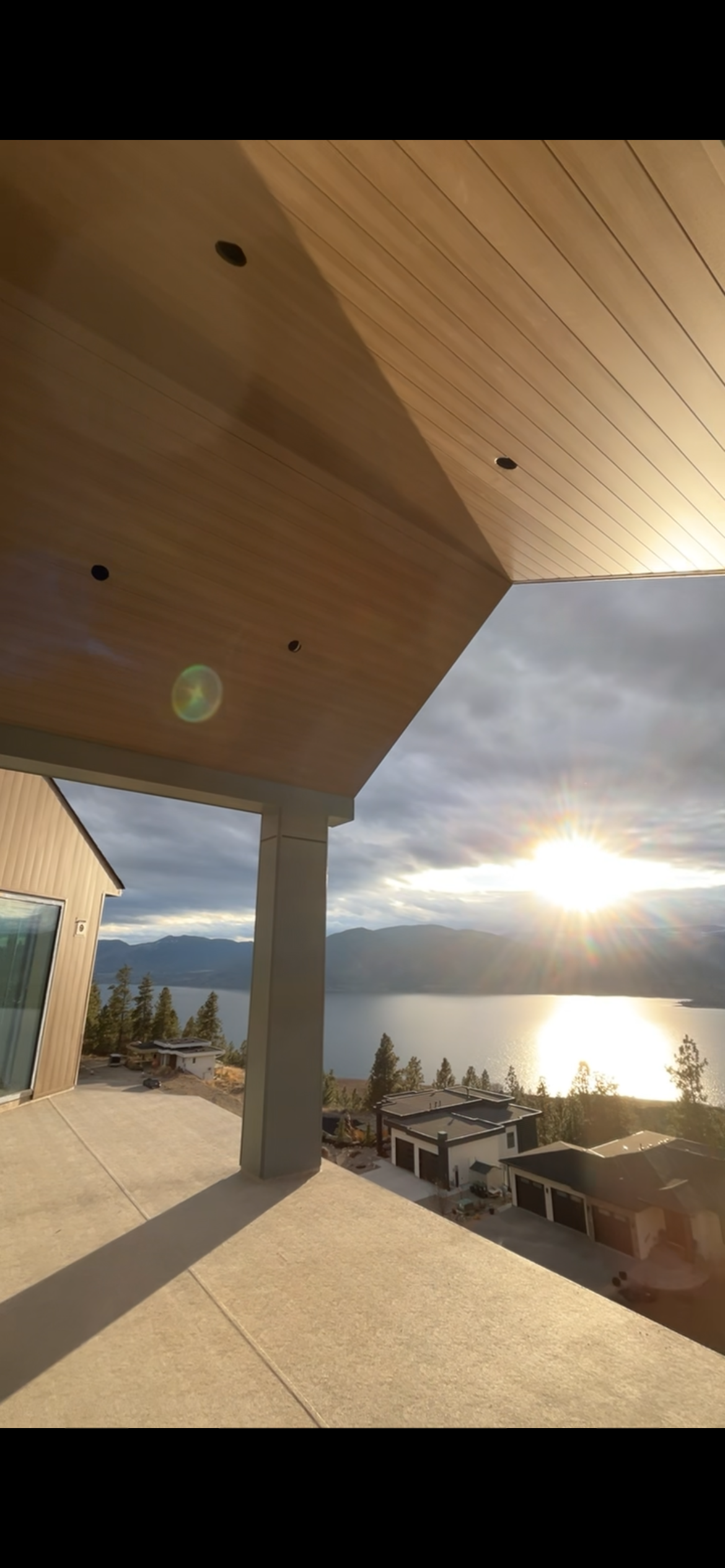 Warm wood-look soffit over a covered patio overlooking Okanagan Lake at sunset